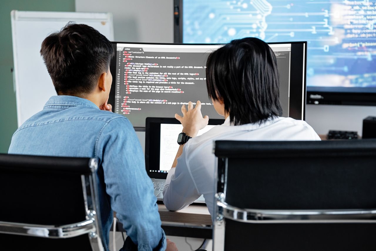 Mastering the First Impression: Your intriguing post title goes here Two developers working together in an office, discussing code on a screen. Technology teamwork setting.